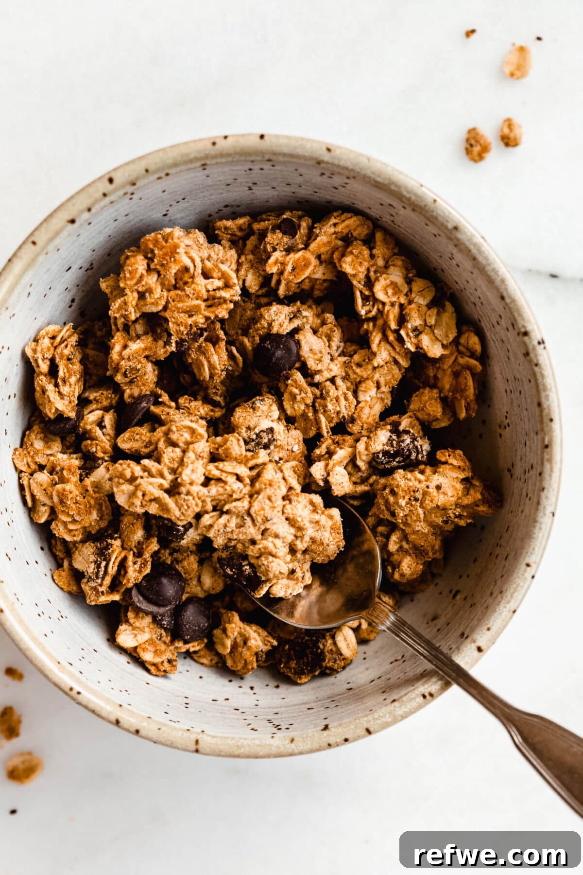 Chocolate Chip Cookie Crunch Granola 10 A charming bowl filled with golden cookie dough granola, a spoon resting enticingly within its crunchy depths.