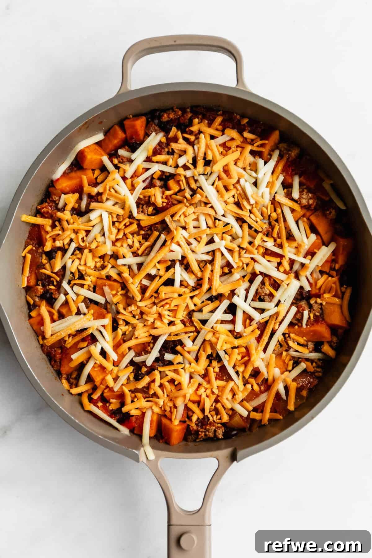 Ground Turkey and Sweet Potato Taco Skillet Recipe 7 shredded cheese on top of ground turkey and sweet potato in a pan.