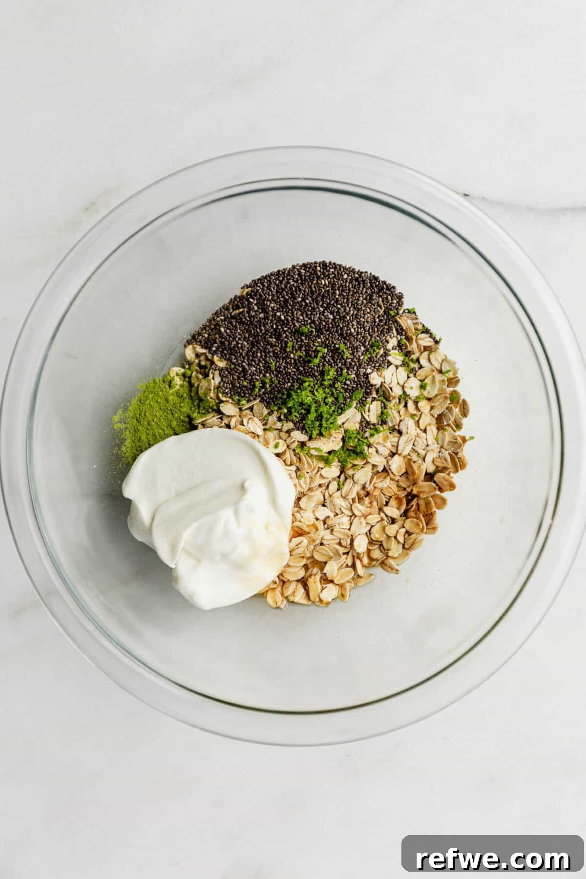 Key Lime Pie Overnight Oats Recipe for Creamy Citrus Breakfast 4 oats, chia seeds, yogurt, lime zest and matcha powder in a clear bowl.