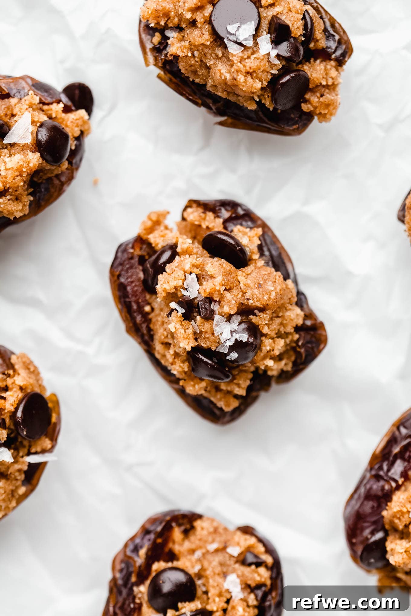 Cookie Dough-Stuffed Dates: Sweet Appetizer with Chocolate Chips 2 cookie dough stuffed dates in a sheet of parchment paper.