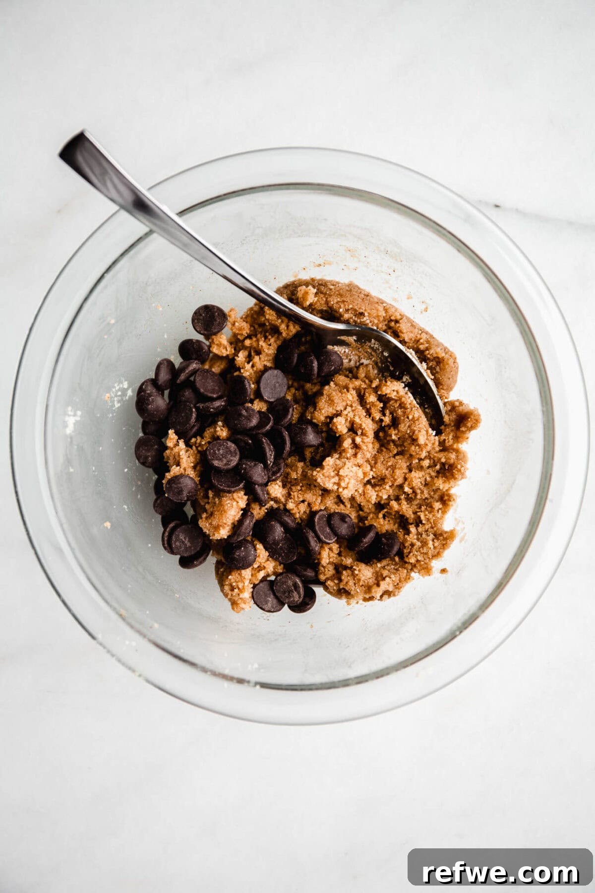 Cookie Dough-Stuffed Dates: Sweet Appetizer with Chocolate Chips 6 no bake cookie dough with chocolate chips in a mixing bowl with a spoon.