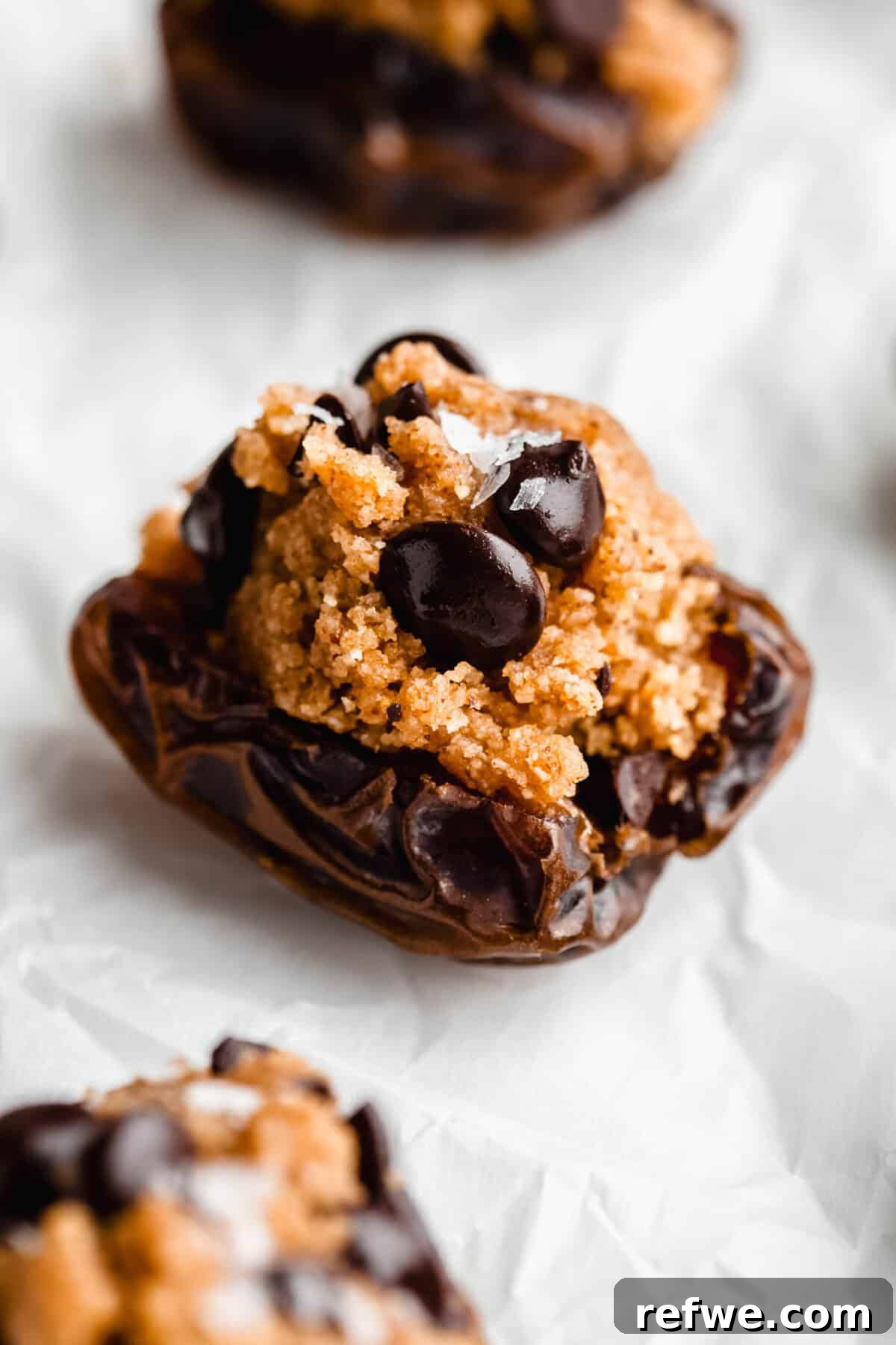 Cookie Dough-Stuffed Dates: Sweet Appetizer with Chocolate Chips 10 a cookie dough stuffed date on parchment paper.