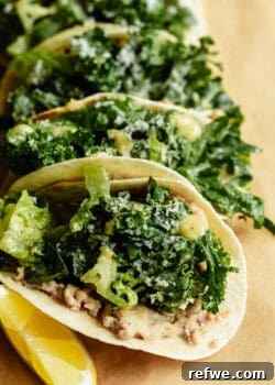 Close-up of chicken caesar smashed tacos loaded with kale caesar salad and parmesan, served with lemon wedges on kraft paper.