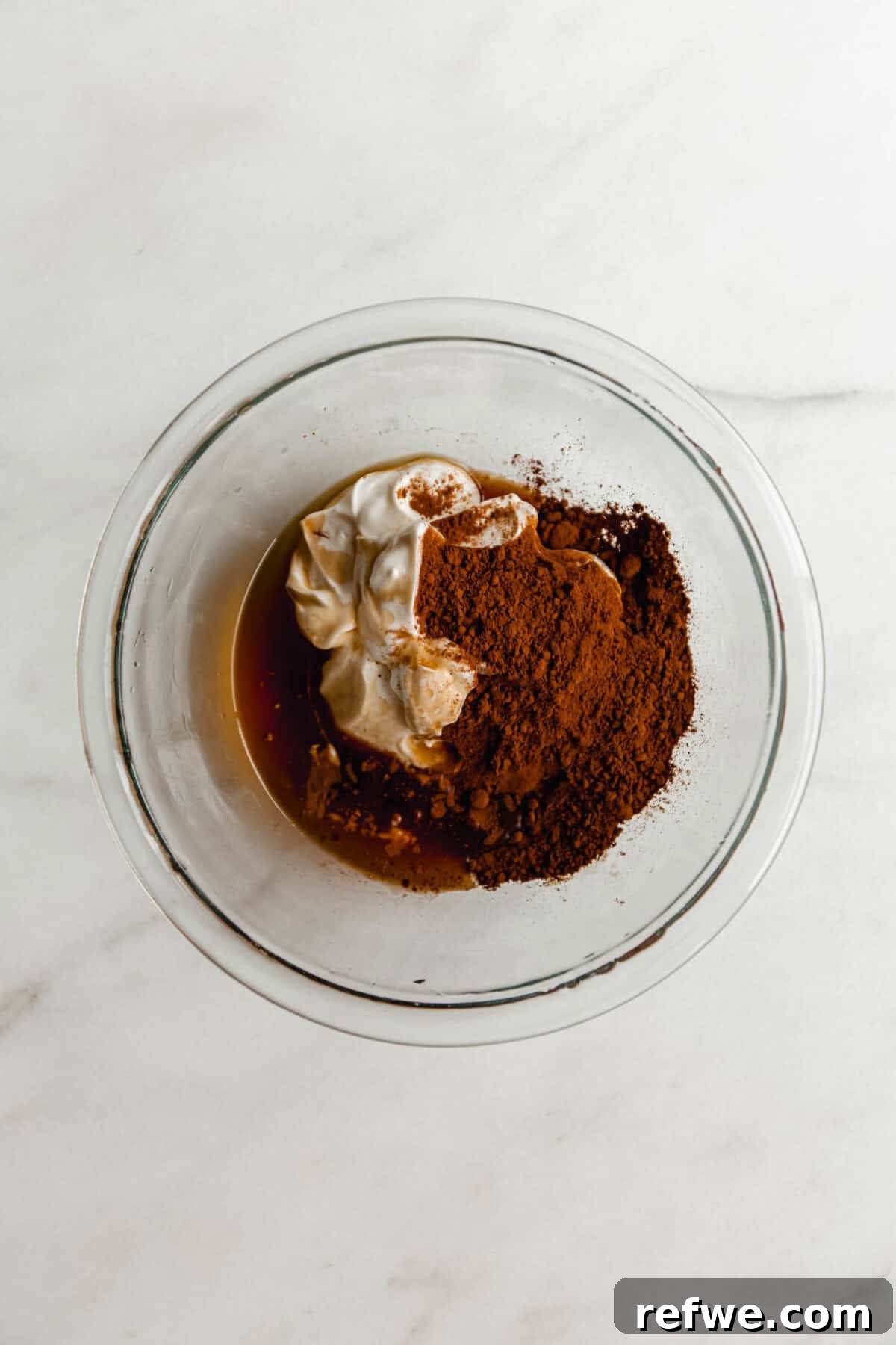 Creamy Greek Yogurt Chocolate Mousse Recipe for Decadent Dessert 4 Ingredients for Greek yogurt chocolate mousse in a glass bowl before mixing, including Greek yogurt, cocoa powder, and maple syrup.