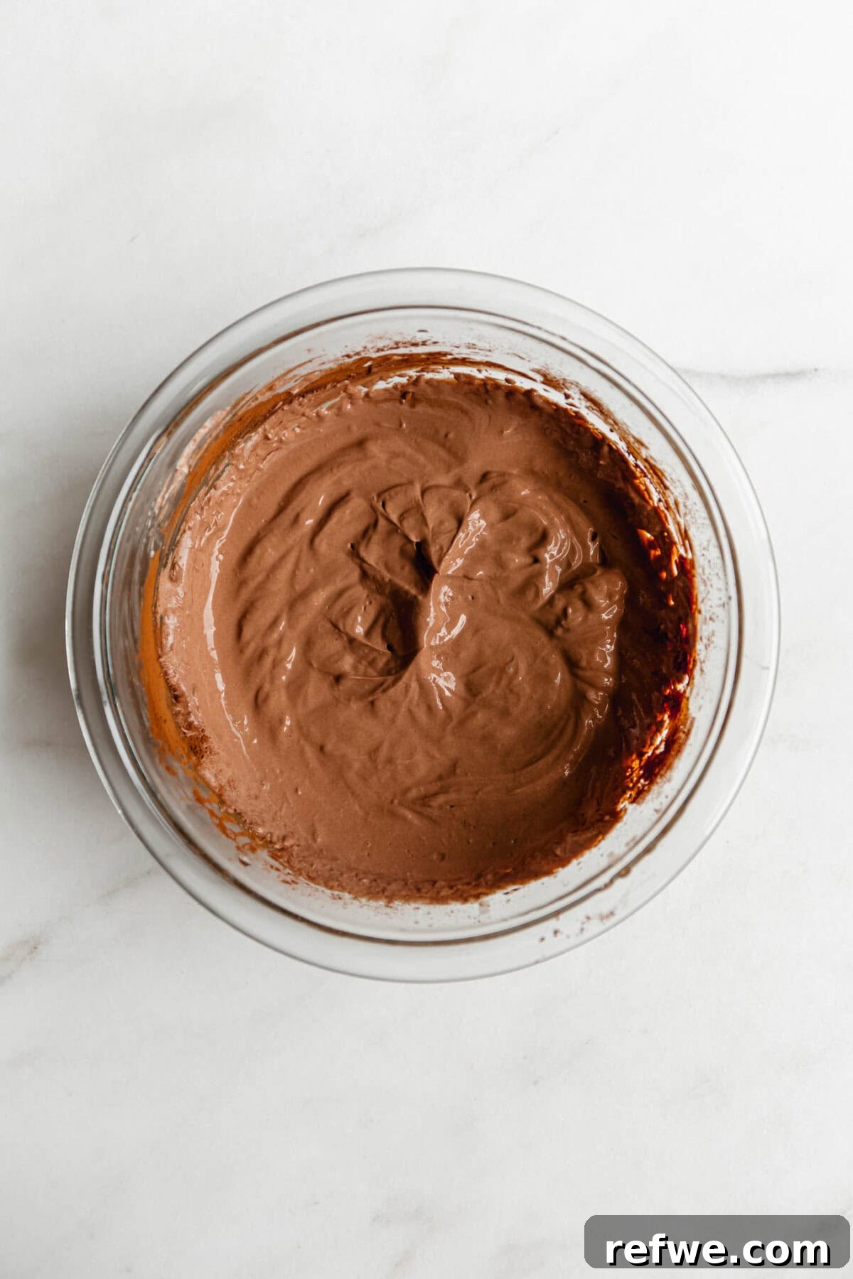 Creamy Greek Yogurt Chocolate Mousse Recipe for Decadent Dessert 6 Greek yogurt chocolate mousse in a glass bowl, viewed from above on a white marble surface.