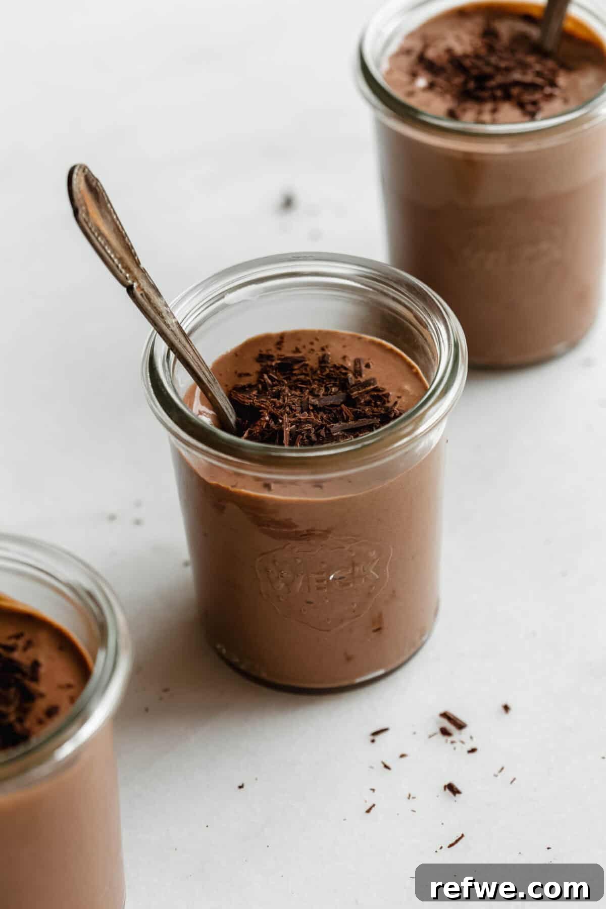 Creamy Greek Yogurt Chocolate Mousse Recipe for Decadent Dessert 7 Multiple glass jars of Greek yogurt chocolate mousse topped with chocolate shavings on a white marble surface.