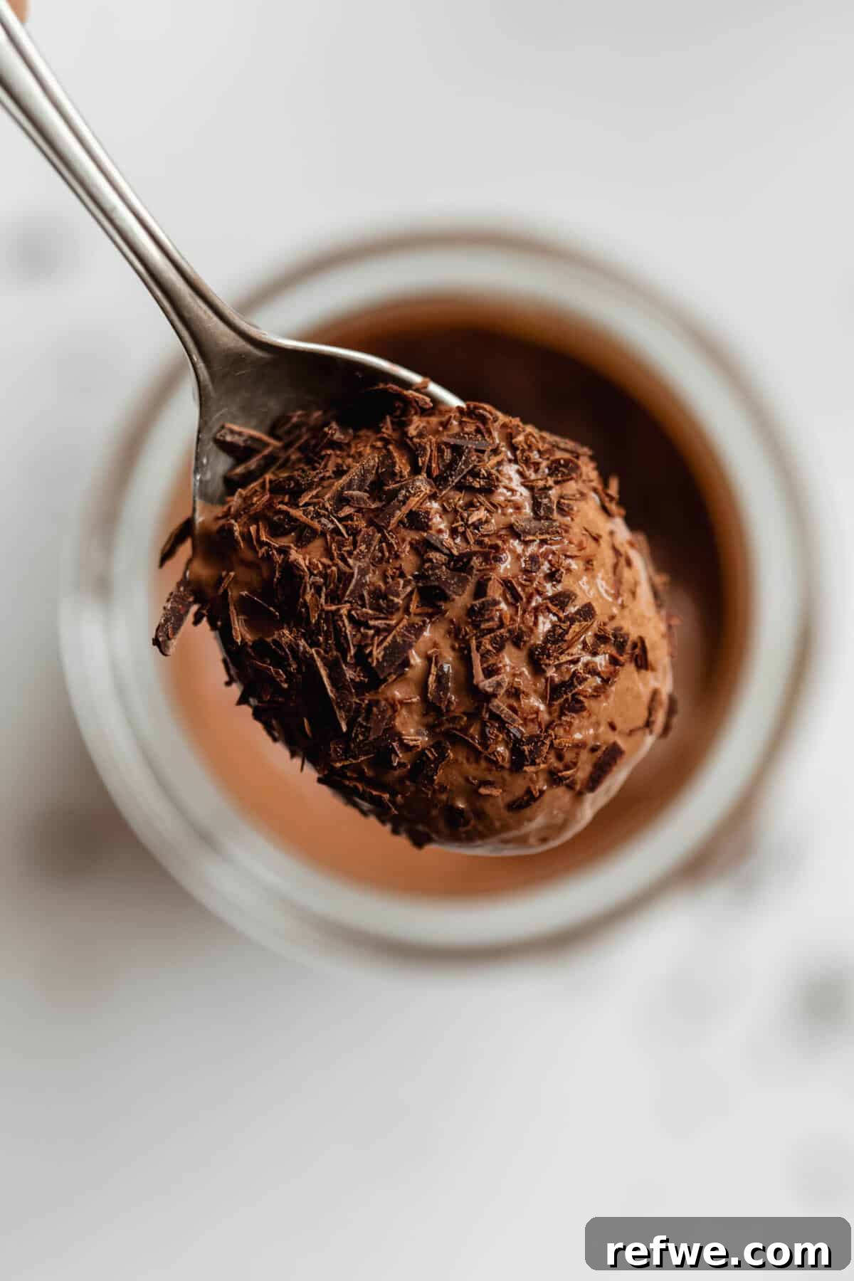 Creamy Greek Yogurt Chocolate Mousse Recipe for Decadent Dessert 8 Close-up of Greek yogurt chocolate mousse in a glass jar piled high with chocolate shavings and a spoon.