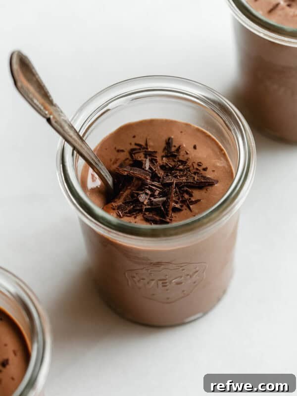 Creamy Greek Yogurt Chocolate Mousse Recipe for Decadent Dessert 10 Greek yogurt chocolate mousse served in glass jars topped with chocolate shavings and a spoon.