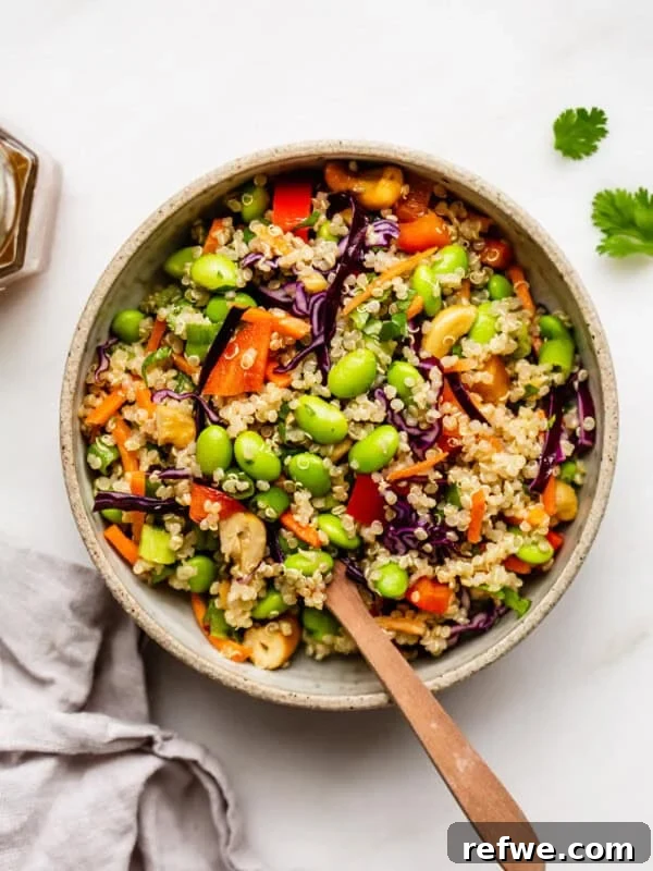 A bowl of edamame salad with a wood spoon in it
