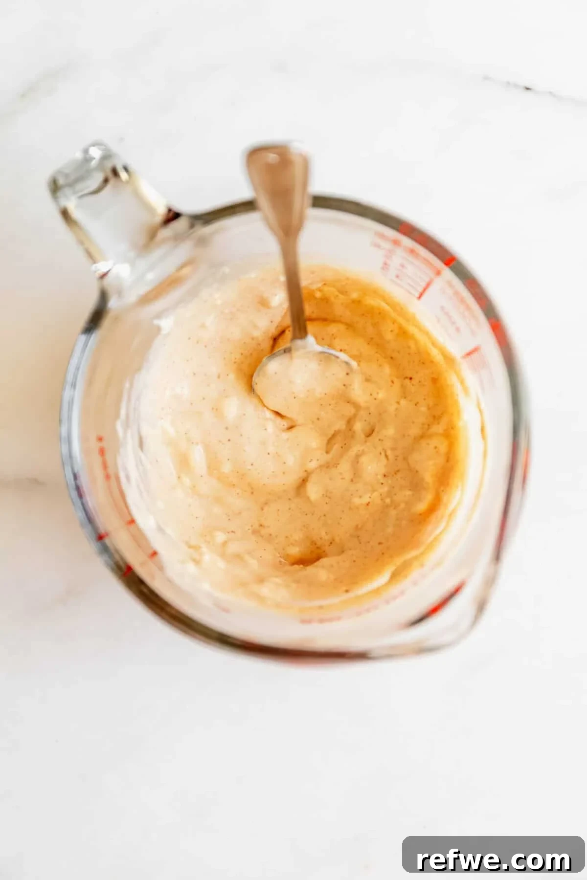 Jalapeño Popper Chicken Salad Recipe — Creamy, Spicy Lunch Idea 5 Cream cheese being stirred with a spoon in a glass measuring cup for the jalapeno popper chicken salad dressing.