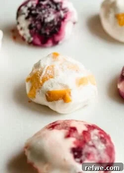 Rice paper mochi balls with blueberry and mango fillings on a white surface.