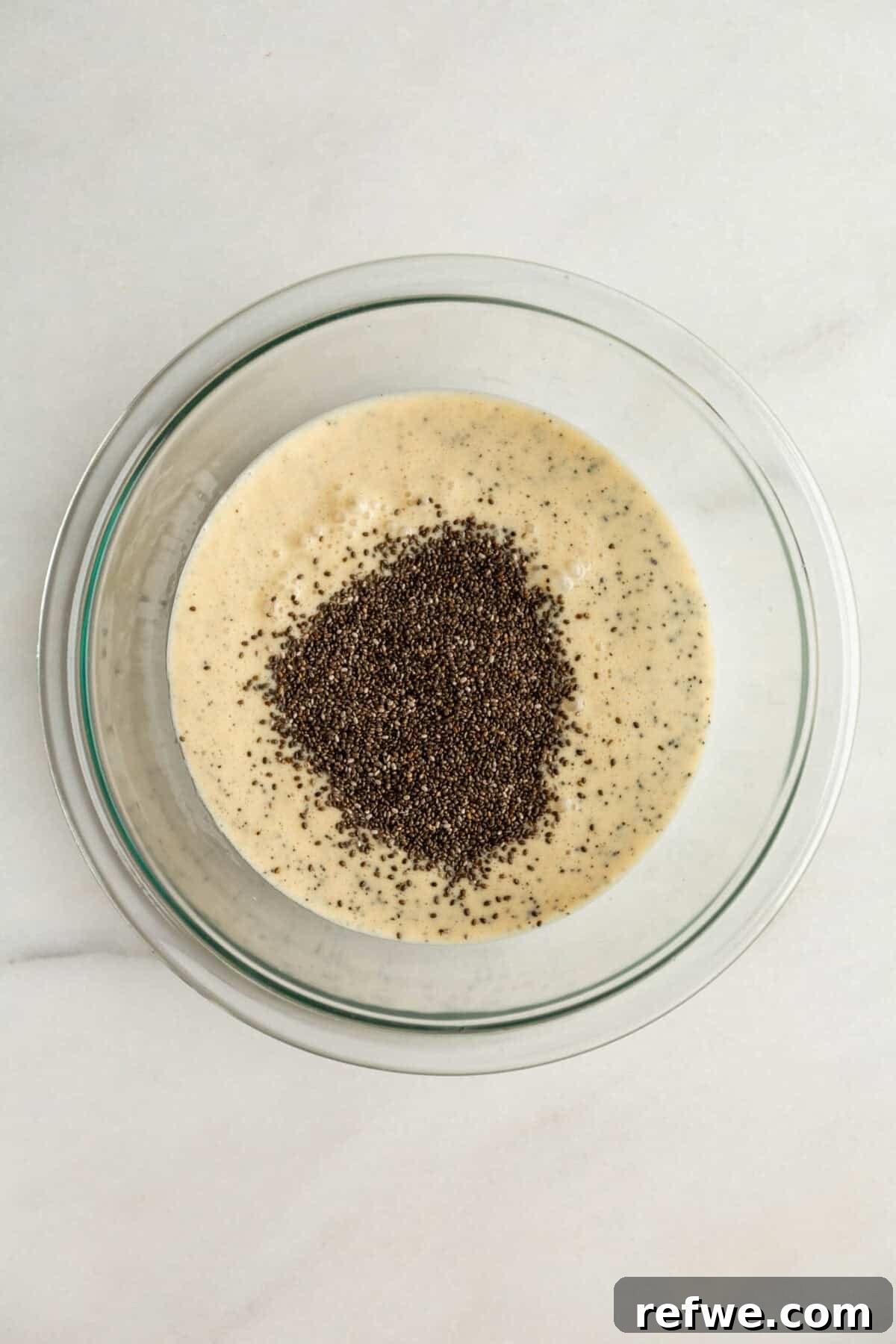Creamy Passionfruit Chia Pudding Recipe for Breakfast & Dessert 7 Adding chia seeds to the liquid mixture in a bowl for passionfruit chia pudding