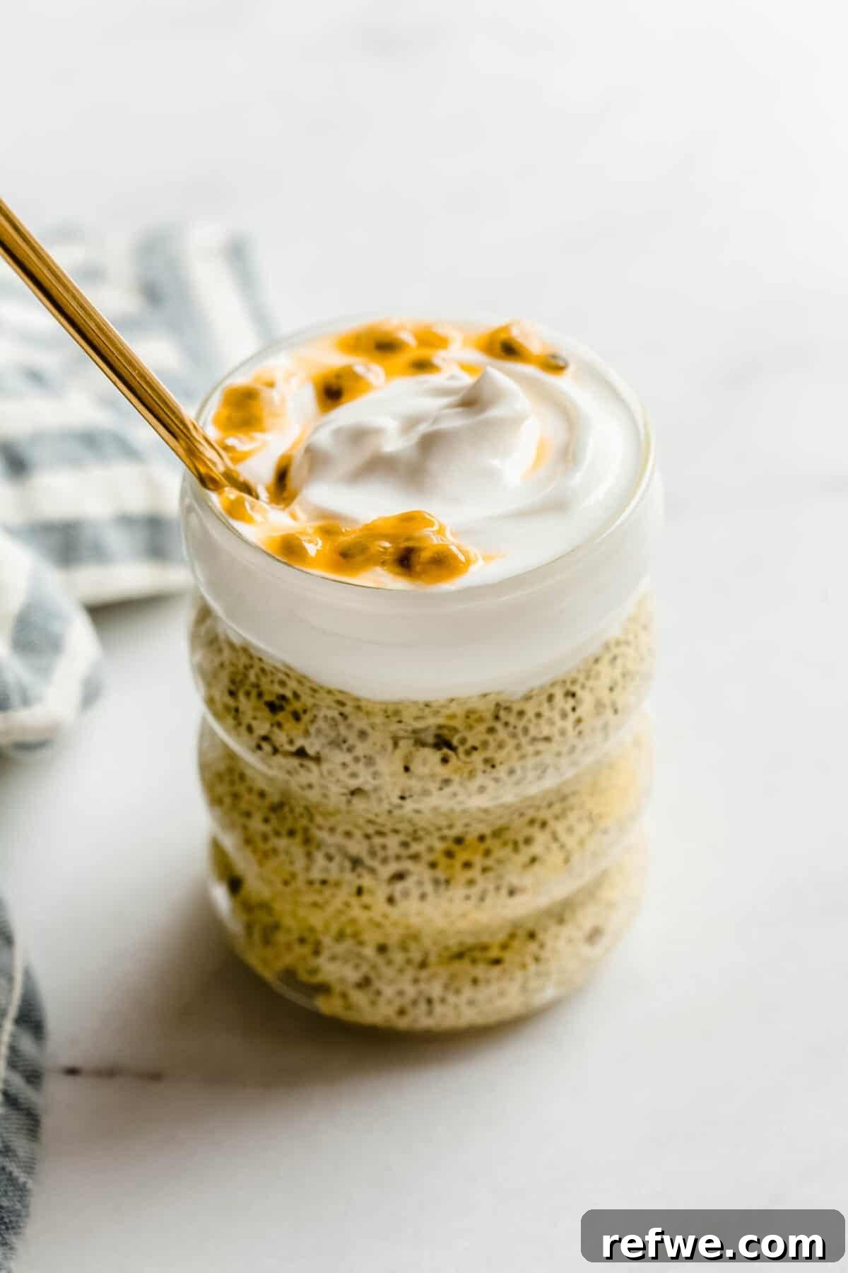 Creamy Passionfruit Chia Pudding Recipe for Breakfast & Dessert 10 Passionfruit chia pudding in a glass jar topped with creamy yogurt and passionfruit pulp, with a gold spoon.