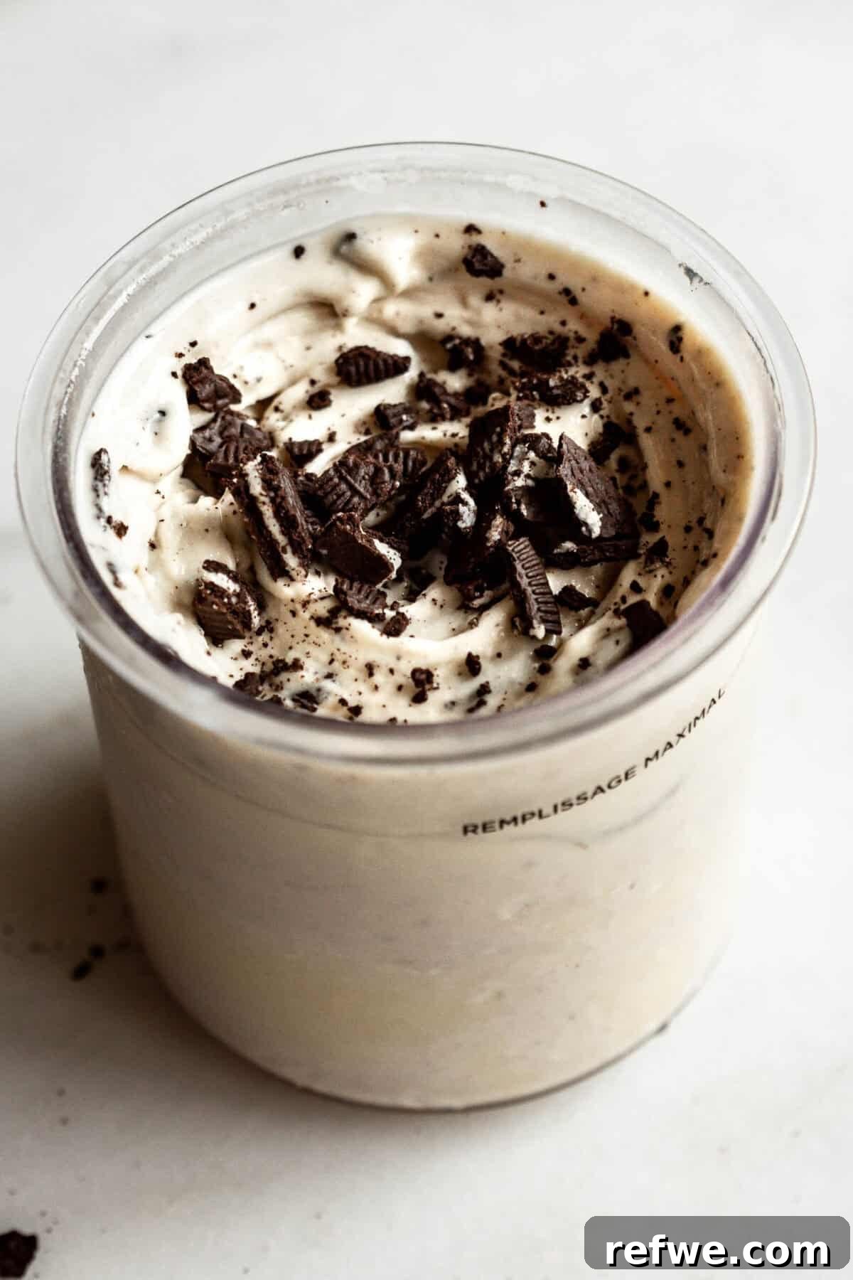 High-Protein Cookies & Cream Recipe for Ninja Creami Ice Cream 2 Cookies and cream Ninja Creami in a container topped with crushed Oreo cookies and chocolate cookie pieces.