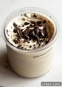 Cookies and cream Ninja Creami in a container topped with crushed Oreo cookies and chocolate cookie pieces.