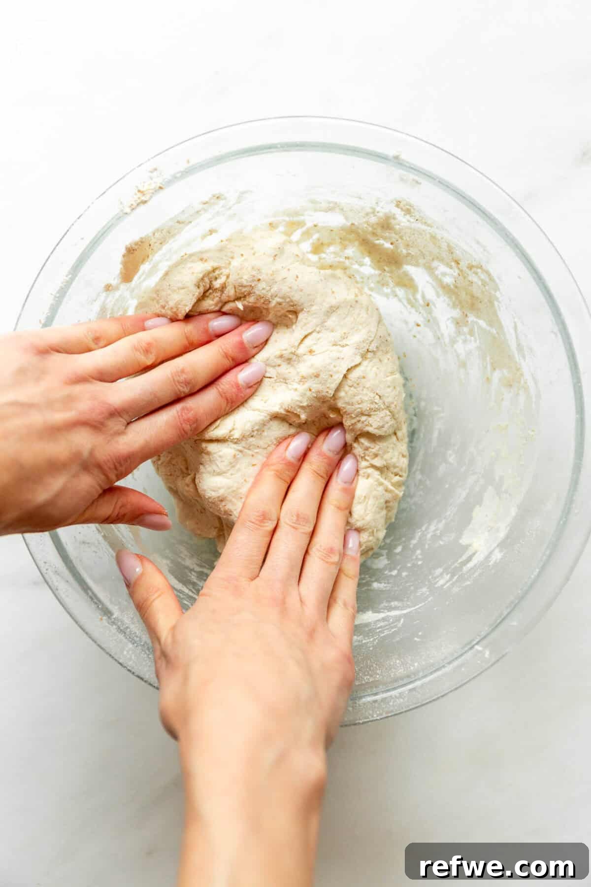 Cottage Cheese Cinnamon Rolls Recipe: Soft and Fluffy 6 Hands kneading cottage cheese cinnamon roll dough in a glass bowl.
