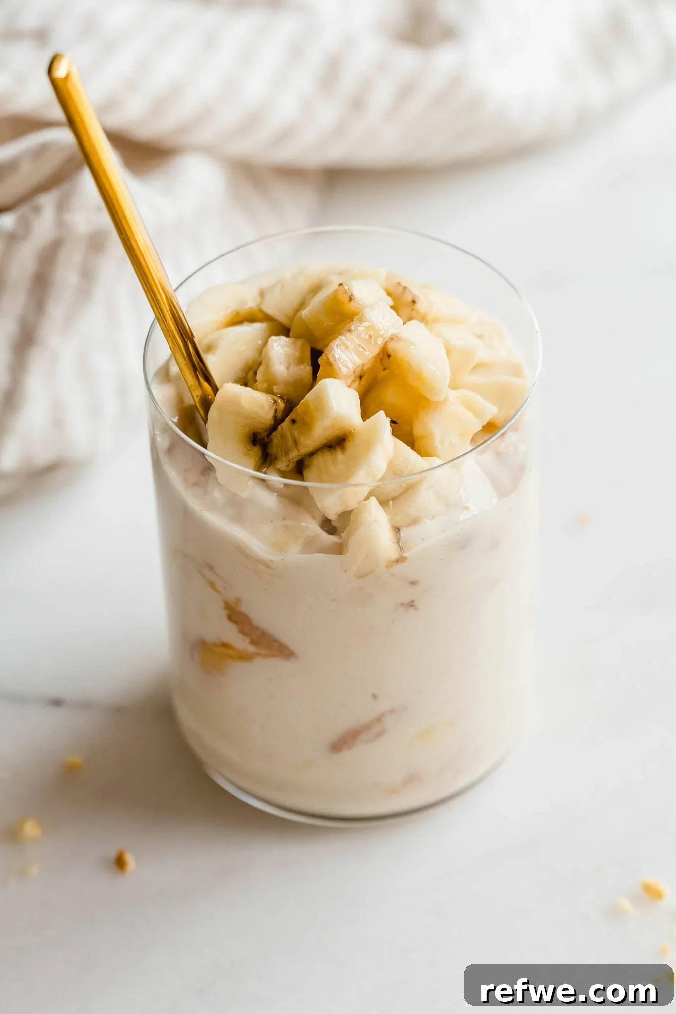 High-Protein Banana Yogurt Pudding Recipe with Greek Yogurt 2 Glass jar of high protein banana pudding being scooped with a gold spoon.