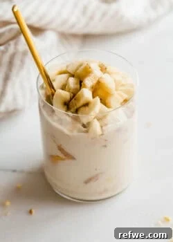 Glass jar of high protein banana pudding being scooped with a gold spoon.