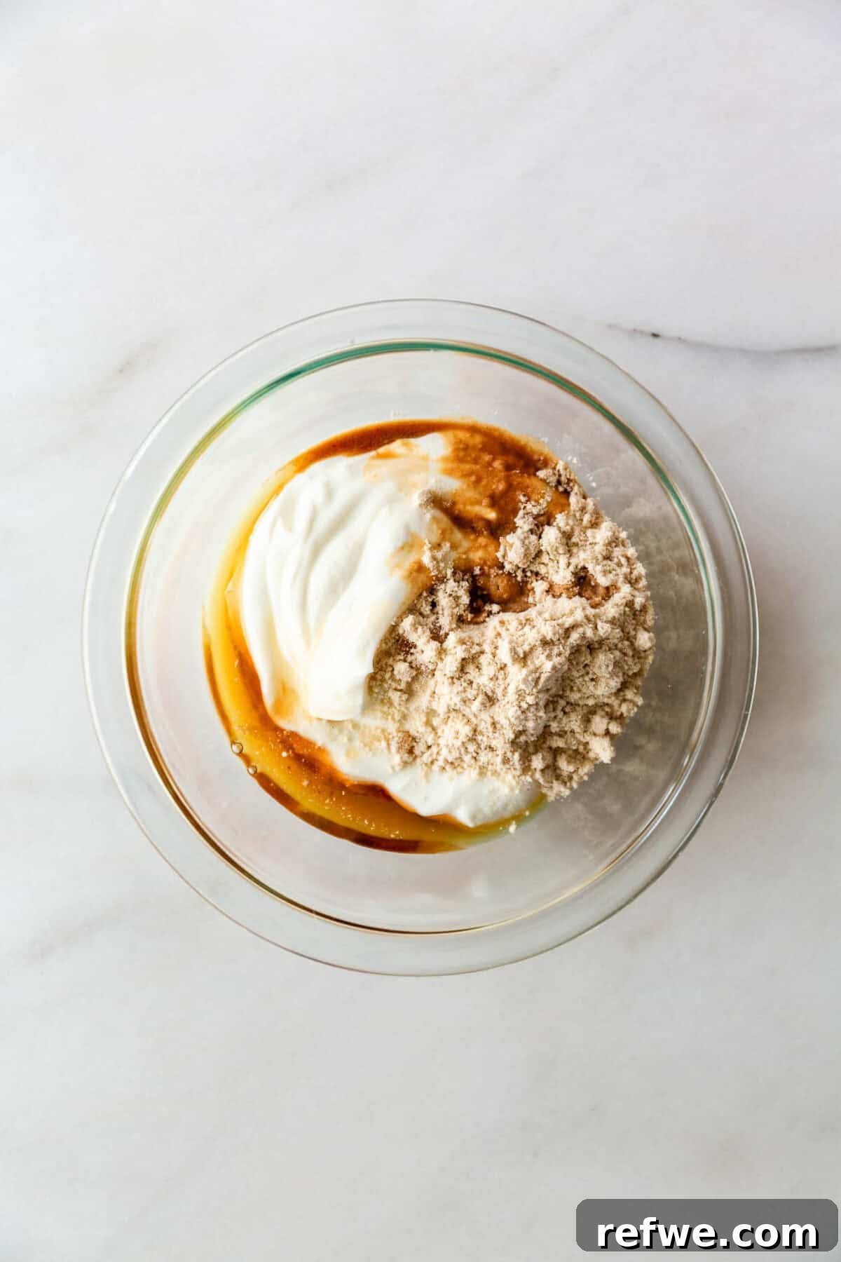 High-Protein Banana Yogurt Pudding Recipe with Greek Yogurt 4 Greek yogurt, protein powder and maple syrup in a clear bowl.