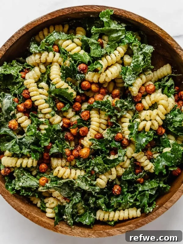 a kale caesar pasta salad in a wood mixing bowl