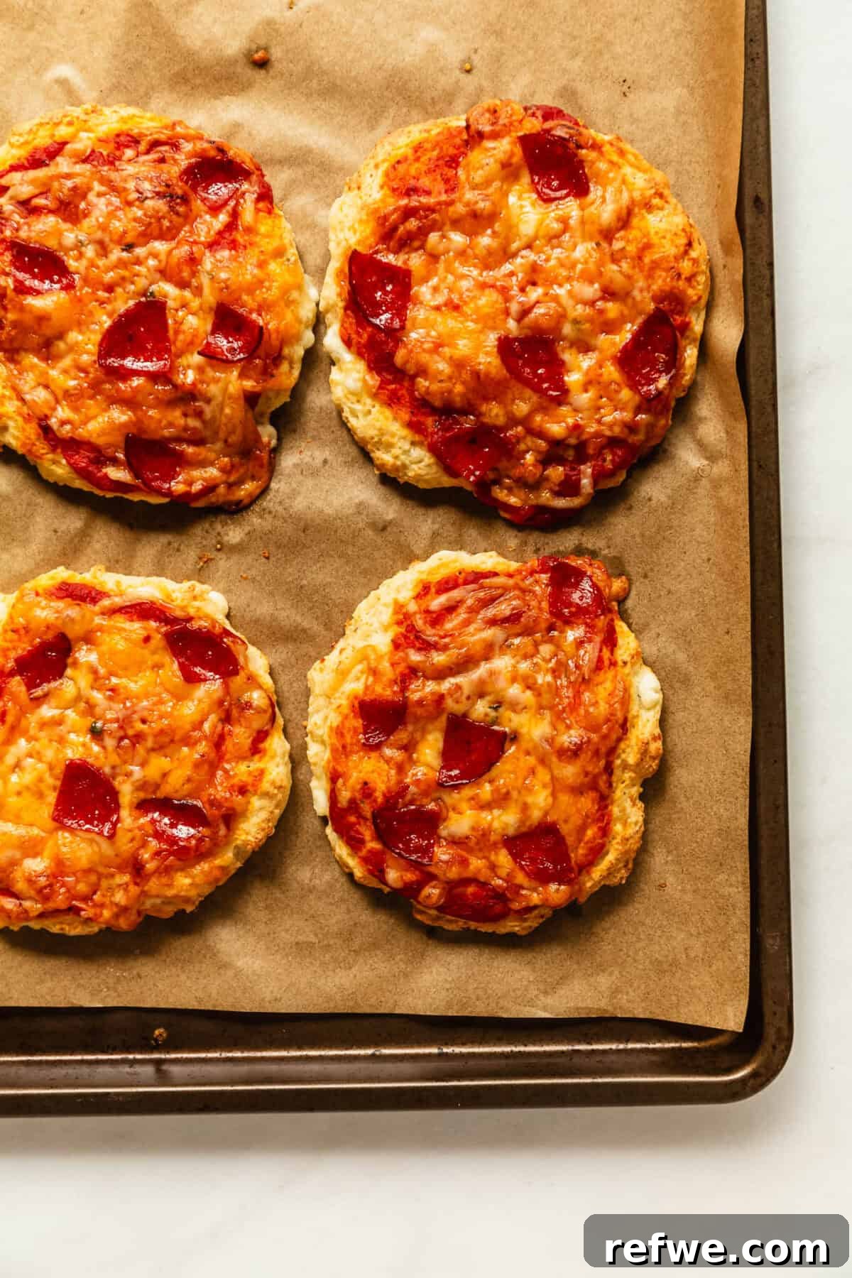 four cottage cheese pizza buns on a baking sheet.