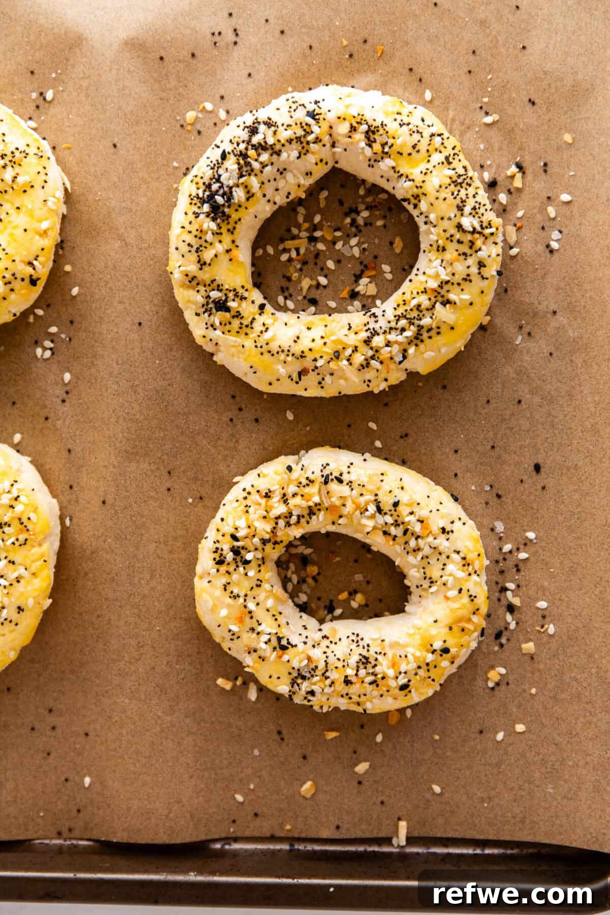 Cottage Cheese and Almond Flour Bagel Recipe 11 unbaked Cottage Cheese Almond Flour Bagels on a baking sheet topped with everything bagel seasoning.