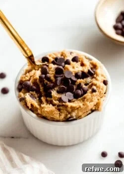 Cottage cheese cookie dough in a white ramekin with a gold spoon in it.