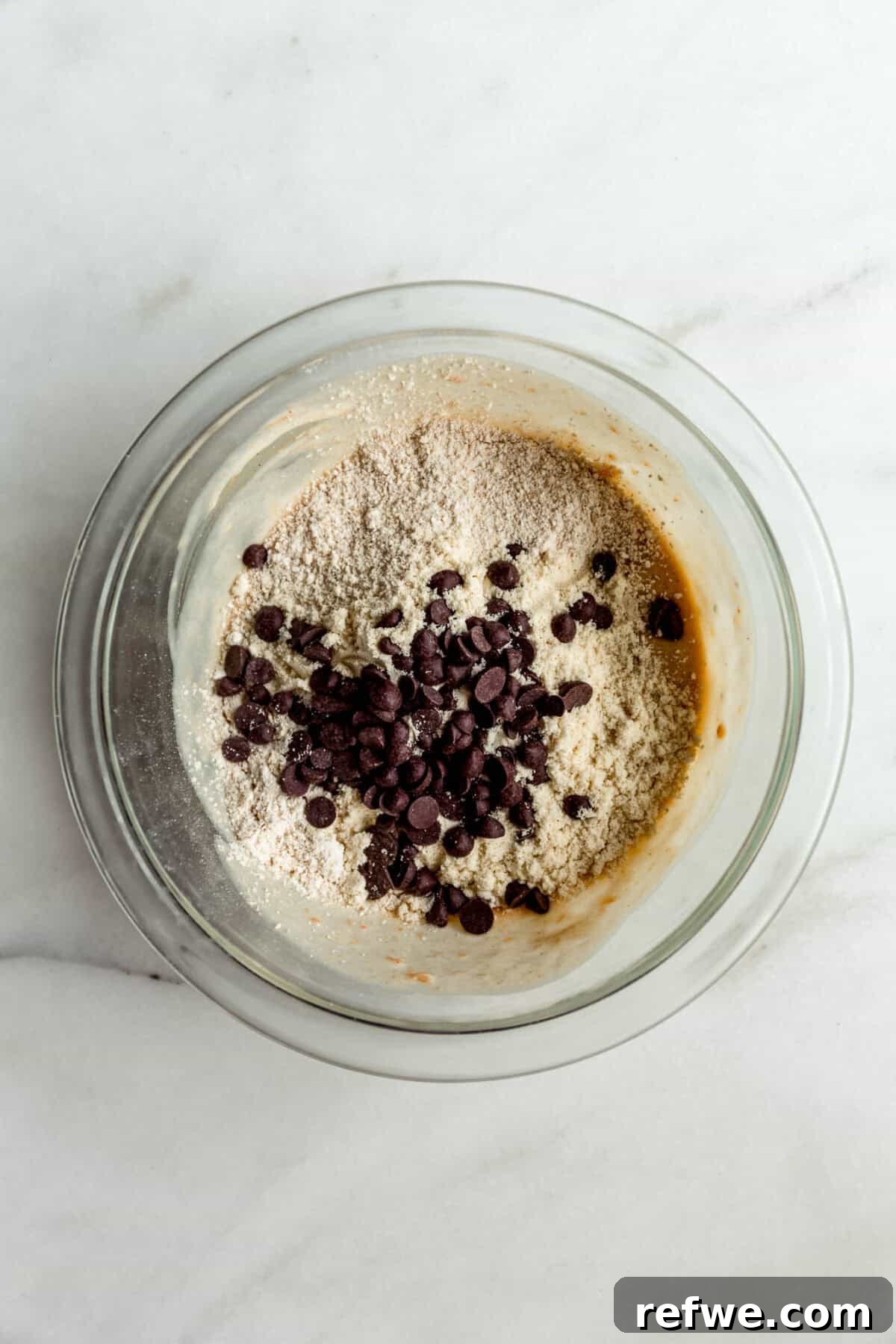 Protein-Packed Cottage Cheese Cookie Dough 5 Oat flour, chocolate chips and cottage cheese mixture in a clear mixing bowl.