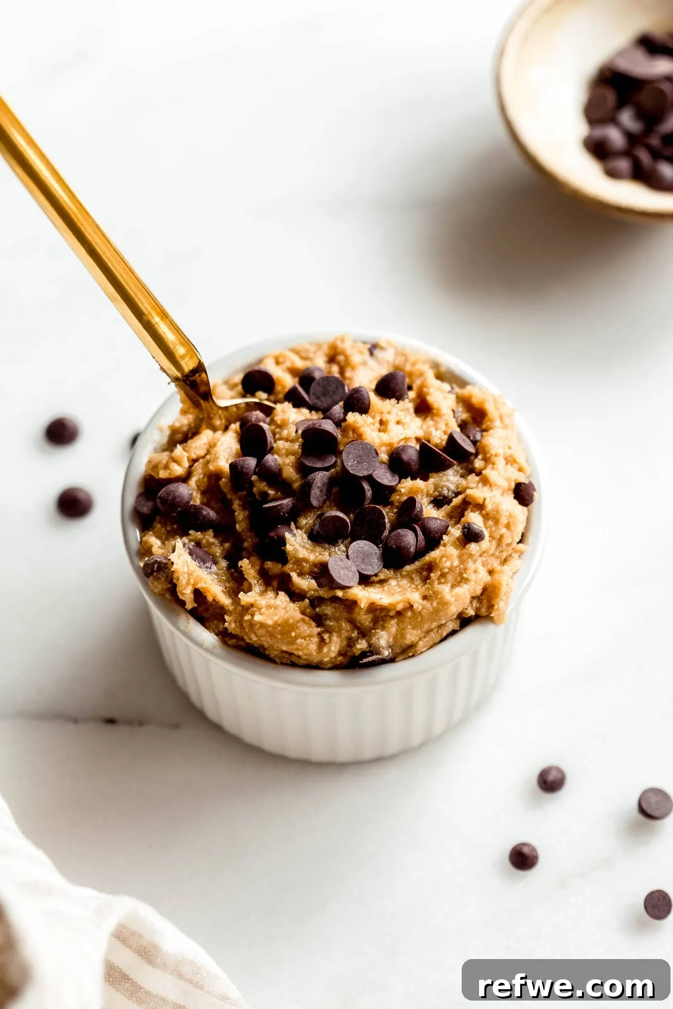 Protein-Packed Cottage Cheese Cookie Dough 8 Cottage cheese cookie dough in a white ramekin with a small bowl of chocolate chips on the side.