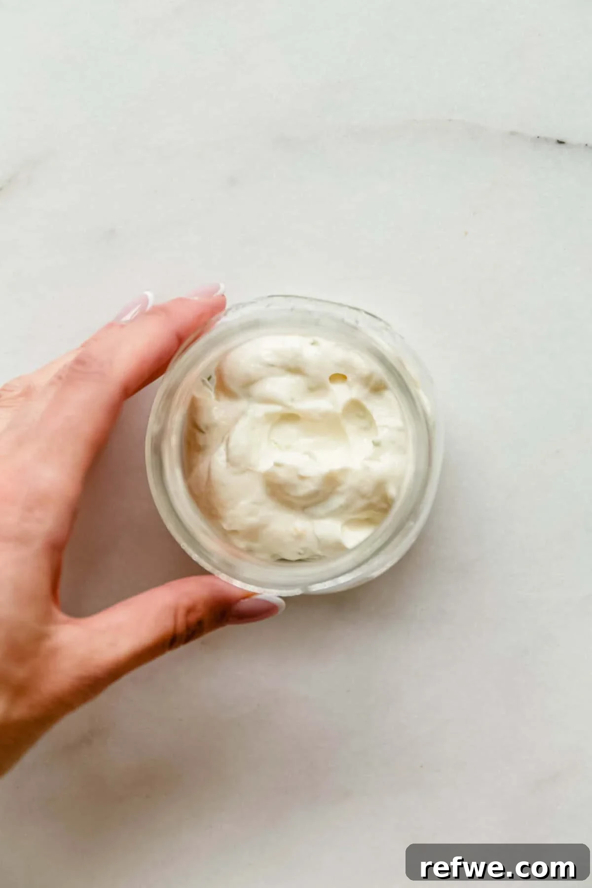 Mini Key Lime Pie Pudding Jars with Greek Yogurt 6 Hand holding a glass jar of creamy key lime pie filling made with Greek yogurt.