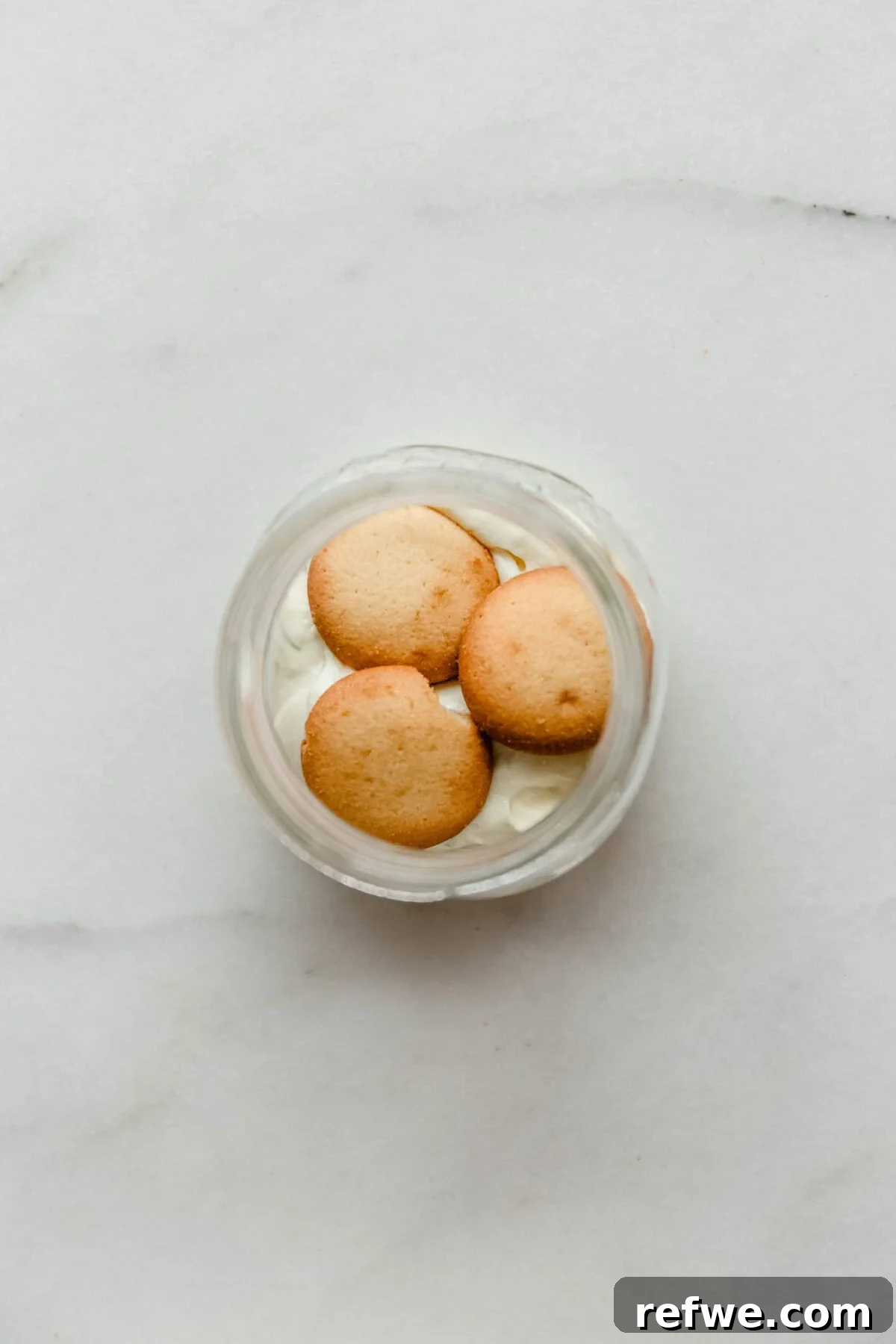 Mini Key Lime Pie Pudding Jars with Greek Yogurt 7 Vanilla cookies layered on top of Greek yogurt filling in a glass jar for key lime pie.