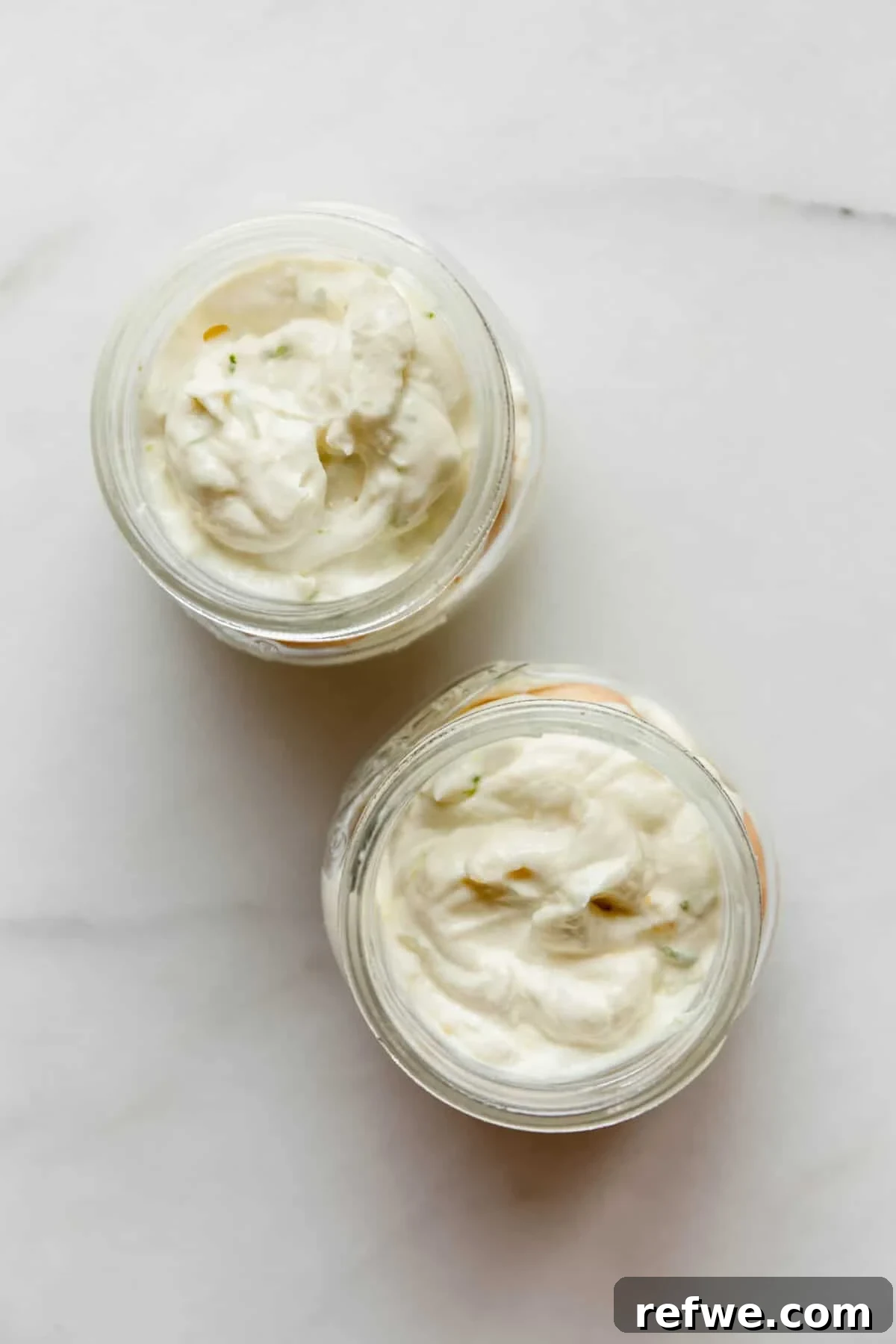 Mini Key Lime Pie Pudding Jars with Greek Yogurt 8 Two glass jars filled with creamy key lime pie yogurt filling, overhead view.