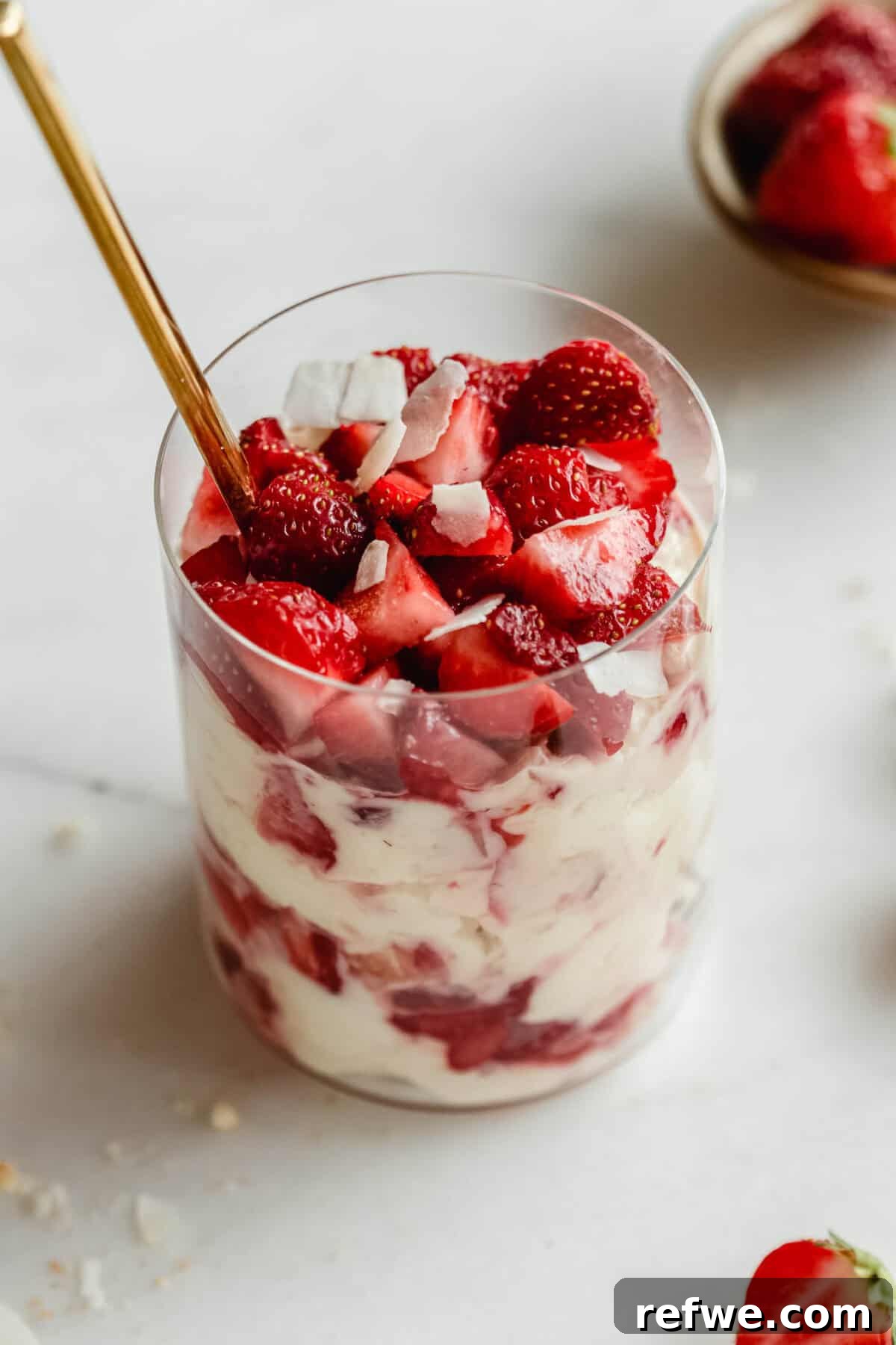 Mini Strawberry Cheesecake Pudding Jars 2 Strawberry pudding jars made with Greek yogurt, Nilla wafers, and vanilla pudding mix with a gold spoon in it.
