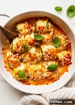 Buffalo chicken zucchini roll ups topped with basil with a wood spoon.