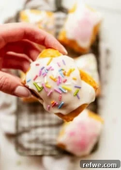 a hand holding a Cottage cheese dough pop tart topped with icing and rainbow sprinkles.