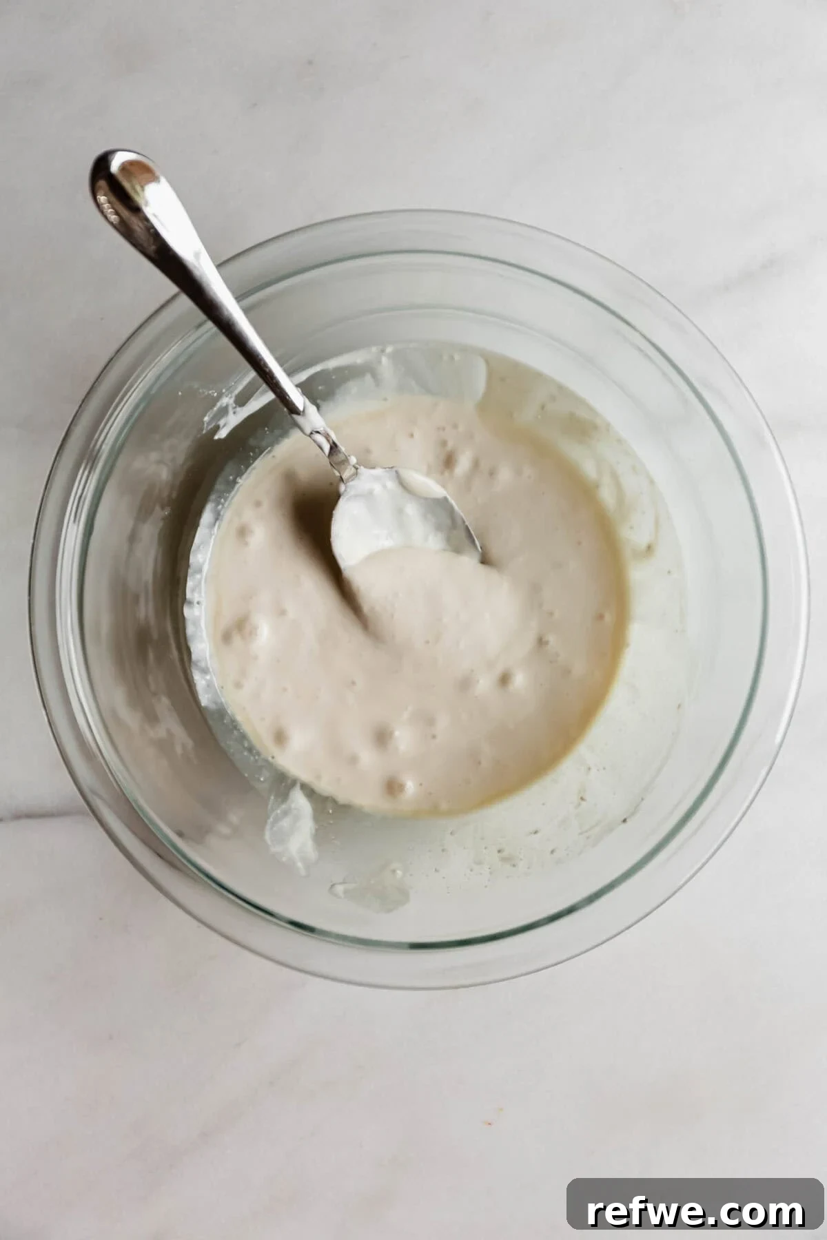 Cottage Cheese Brownie Batter Recipe 6 blended cottage cheese with a spoon in a clear mixing bowl.