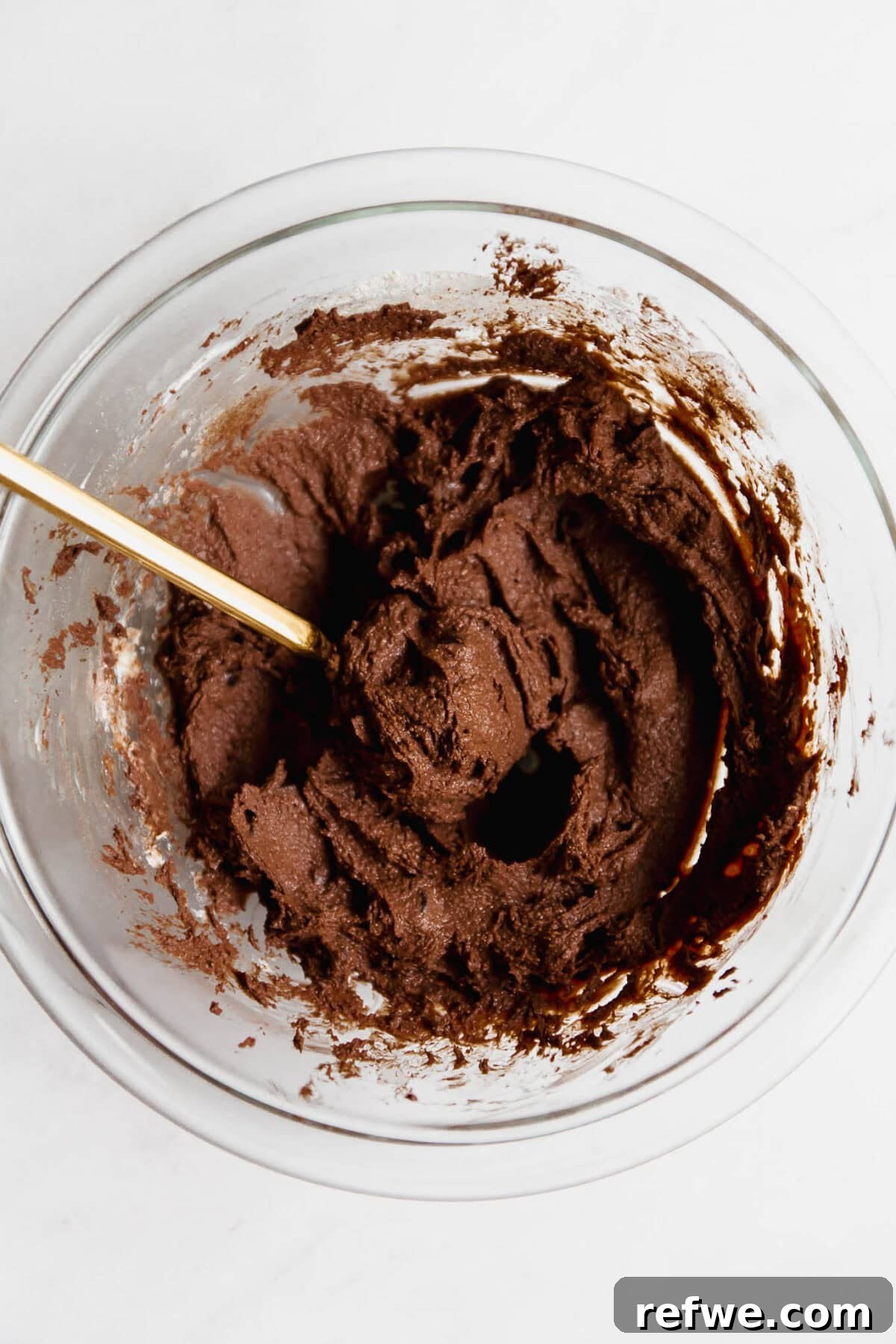 Cottage Cheese Brownie Batter Recipe 9 Cottage cheese brownie batter in a clear mixing bowl with a gold spoon.