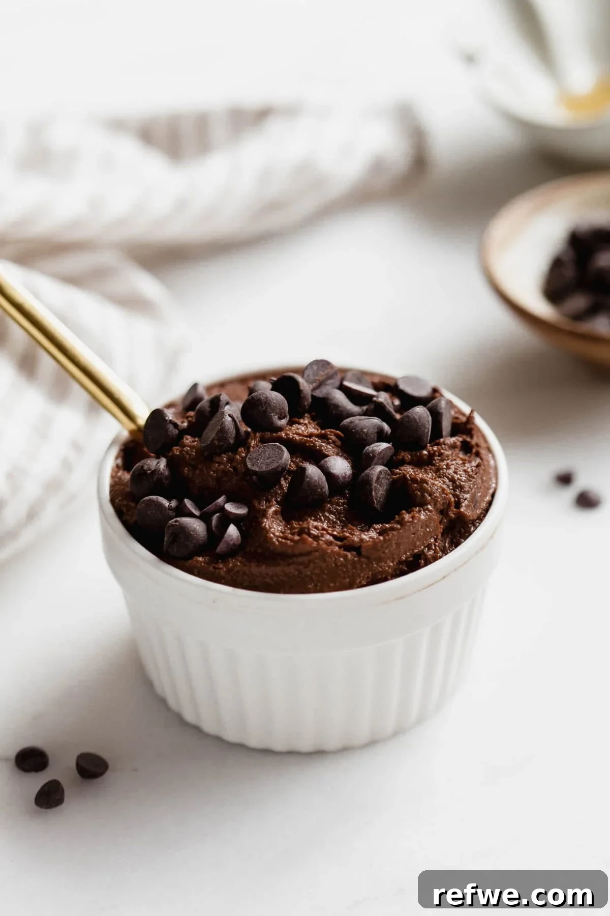Cottage Cheese Brownie Batter Recipe 10 Cottage cheese brownie batter in a white ramekin with a gold spoon with a napkin on the side.