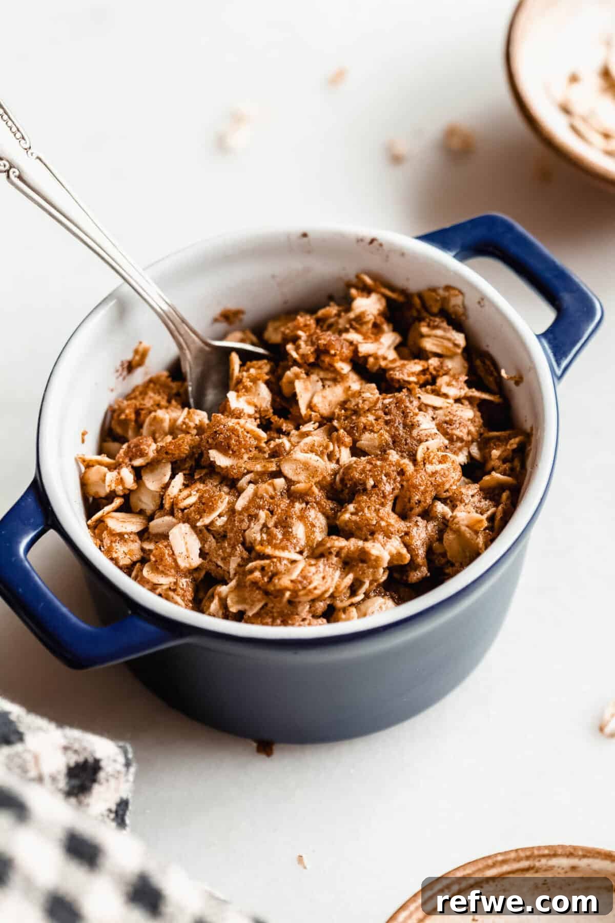 Air Fryer Apple Crisp Recipe — Quick Fall Dessert 8 A spoon scooping into a baked apple crisp with a crispy golden brown oat topping.