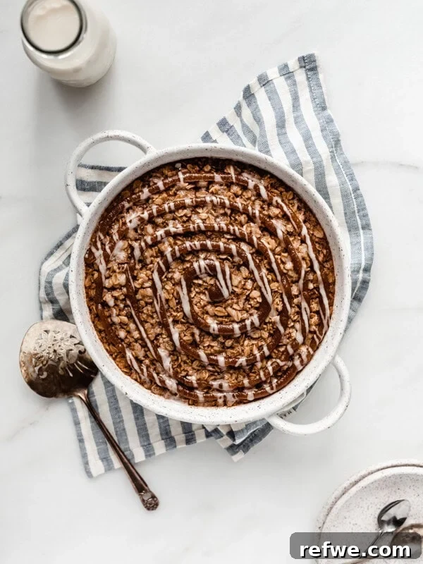 baked oatmeal in a round baking dish on a striped blue napkin topped with cinnamon sugar swirl
