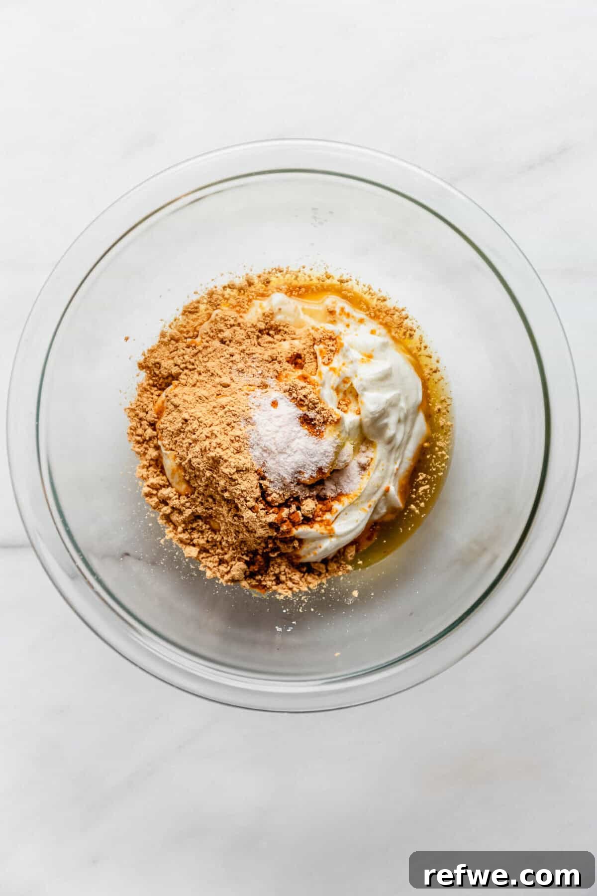 Creamy Greek Yogurt Peanut Butter Mousse Recipe 5 Bowl of Greek yogurt, peanut butter powder, and maple syrup before mixing into mousse.