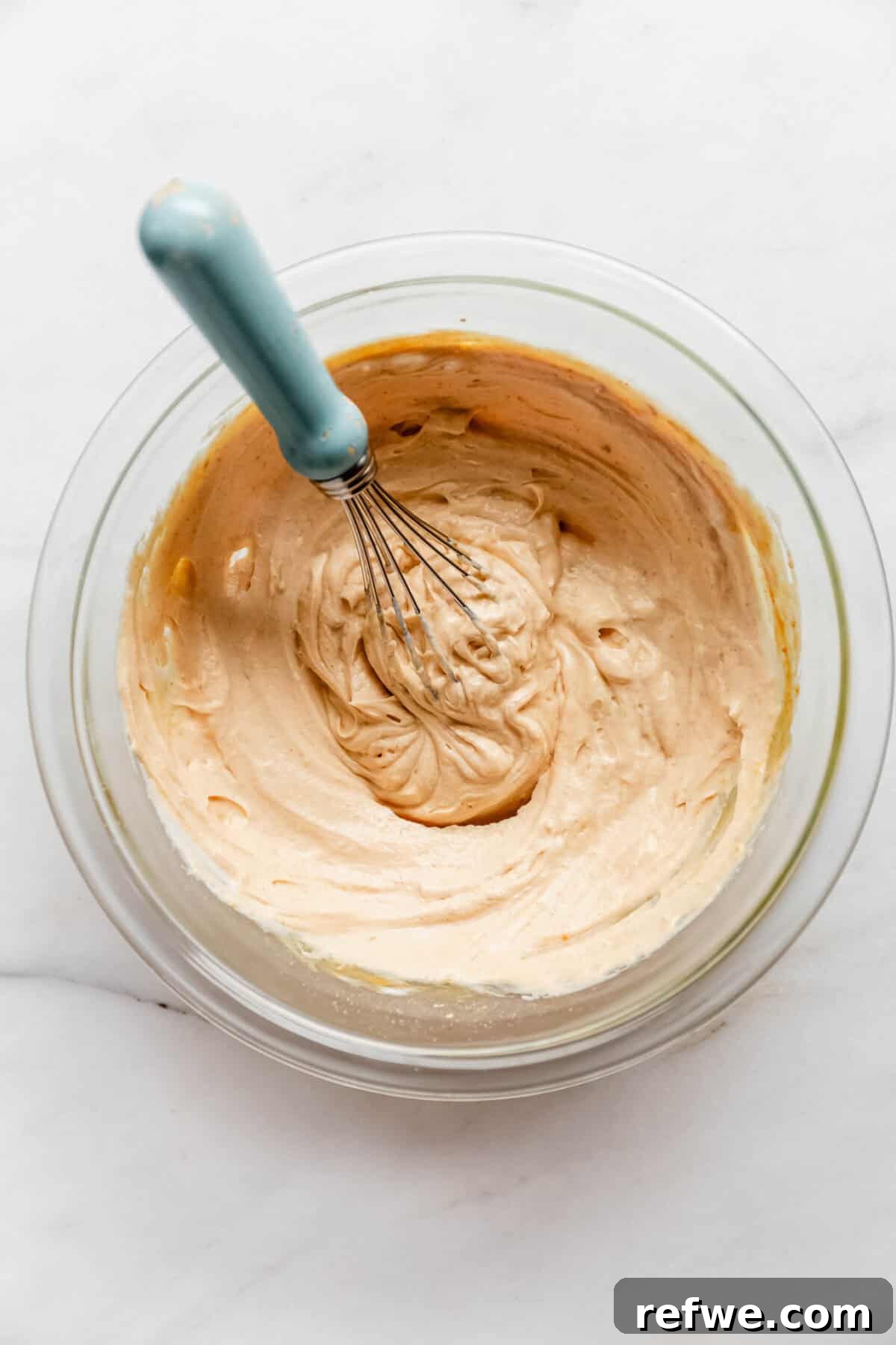 Creamy Greek Yogurt Peanut Butter Mousse Recipe 6 Whisking a creamy peanut butter mousse mixture in a glass bowl.