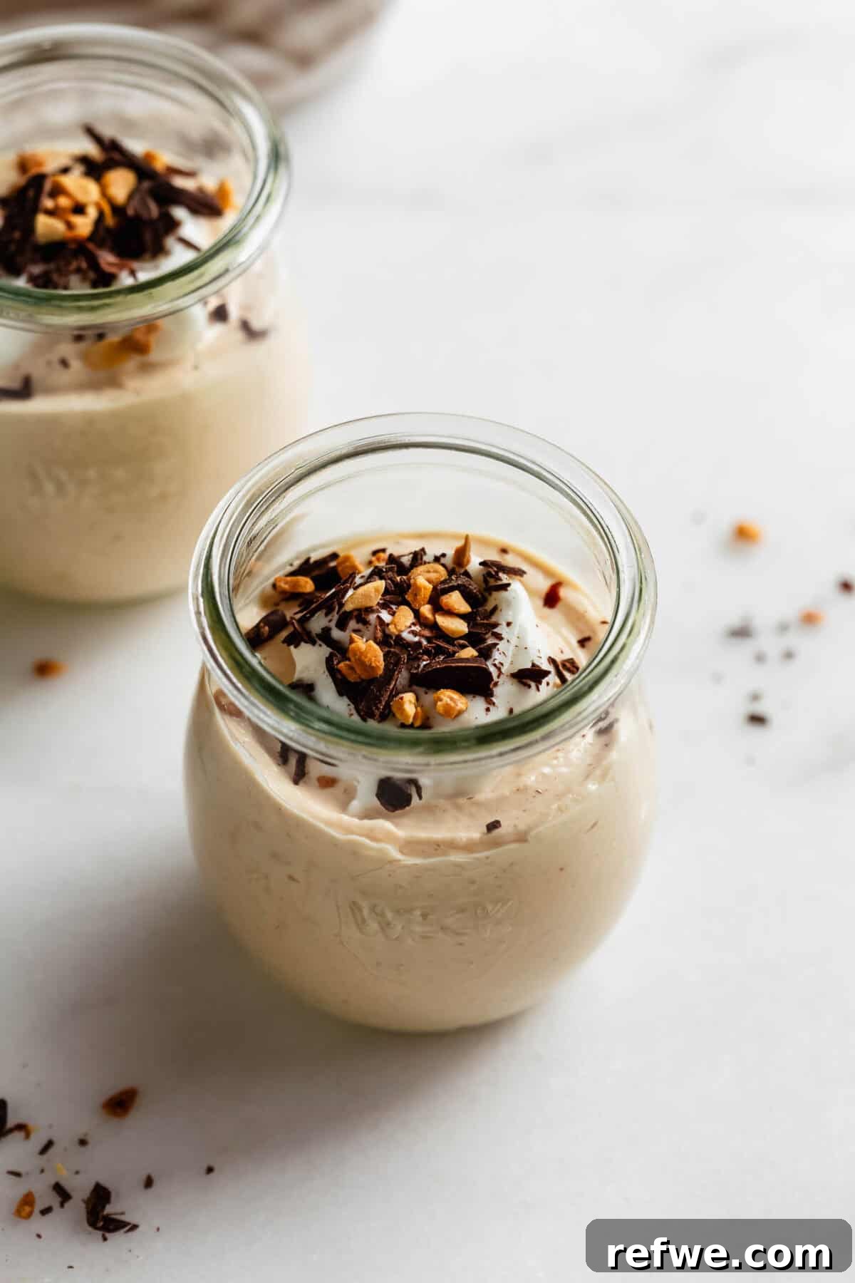 Creamy Greek Yogurt Peanut Butter Mousse Recipe 7 Close-up of a jar of Greek yogurt peanut butter mousse garnished with chopped nuts and chocolate shavings.