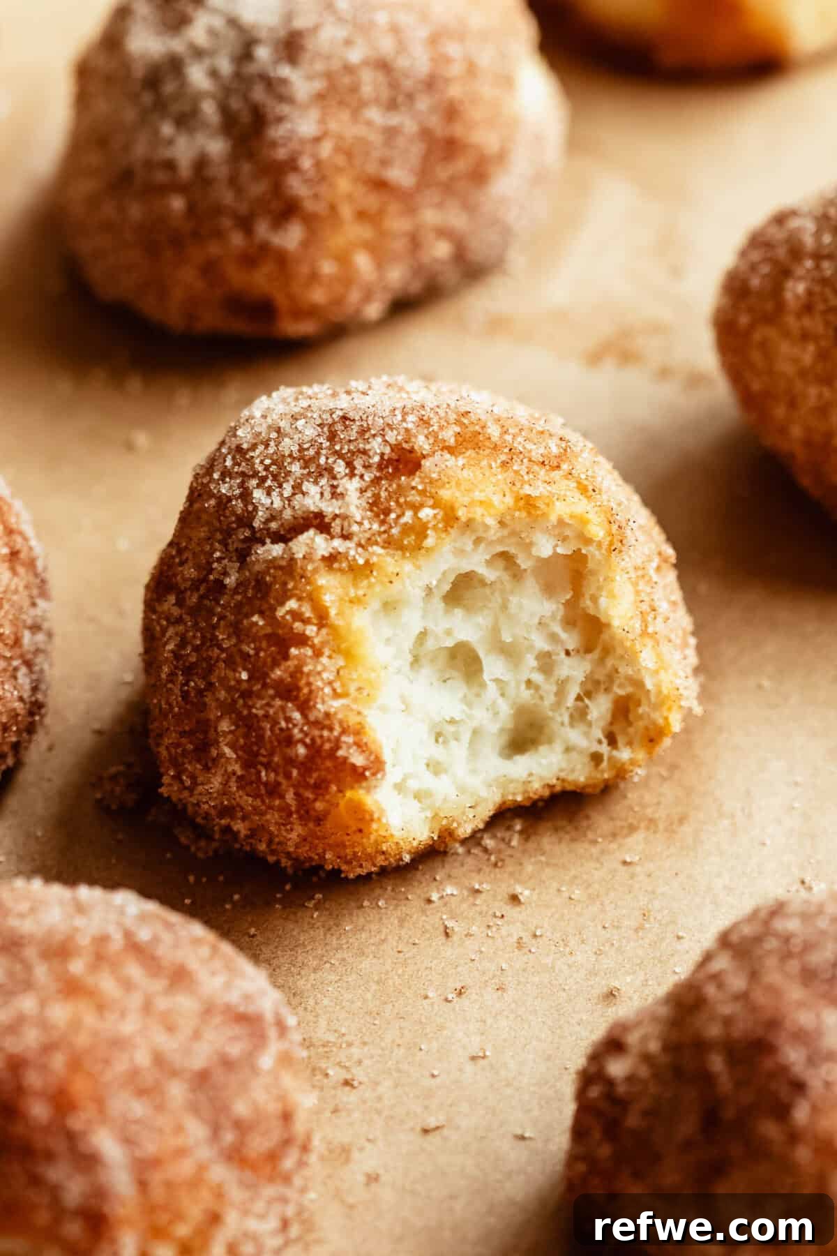 Baked Cottage Cheese Donut Holes Recipe 12 A cinnamon sugar donut hole torn open to reveal its soft, fluffy interior, surrounded by more donut holes.
