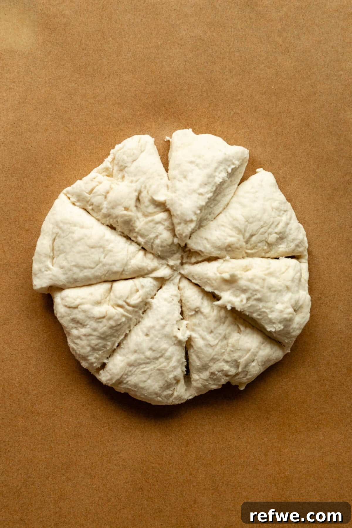 Baked Cottage Cheese Donut Holes Recipe 7 A round disc of dough scored into eight wedges on a piece of parchment paper.