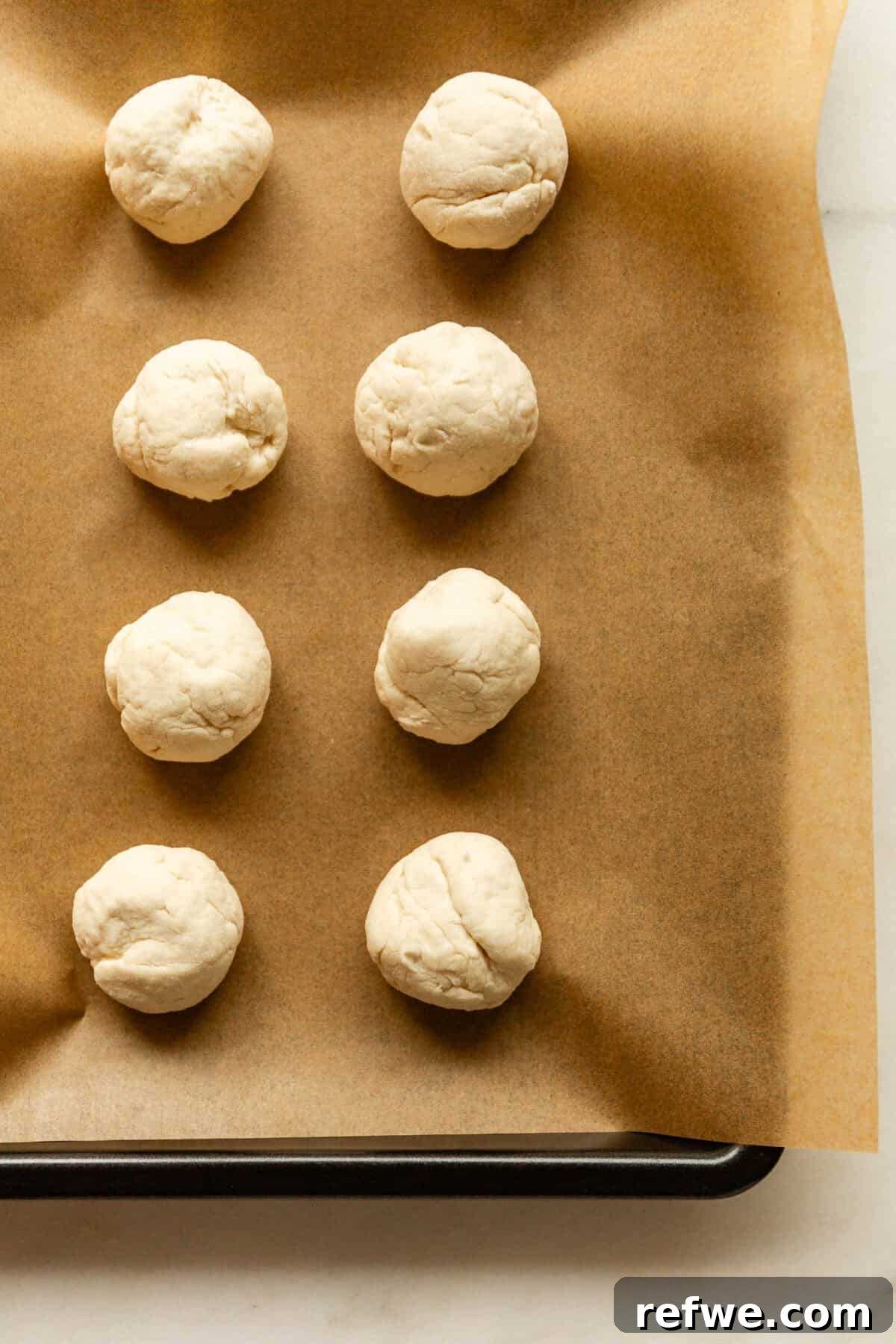 Baked Cottage Cheese Donut Holes Recipe 8 Rows of round dough balls arranged on a parchment-lined baking sheet before baking.