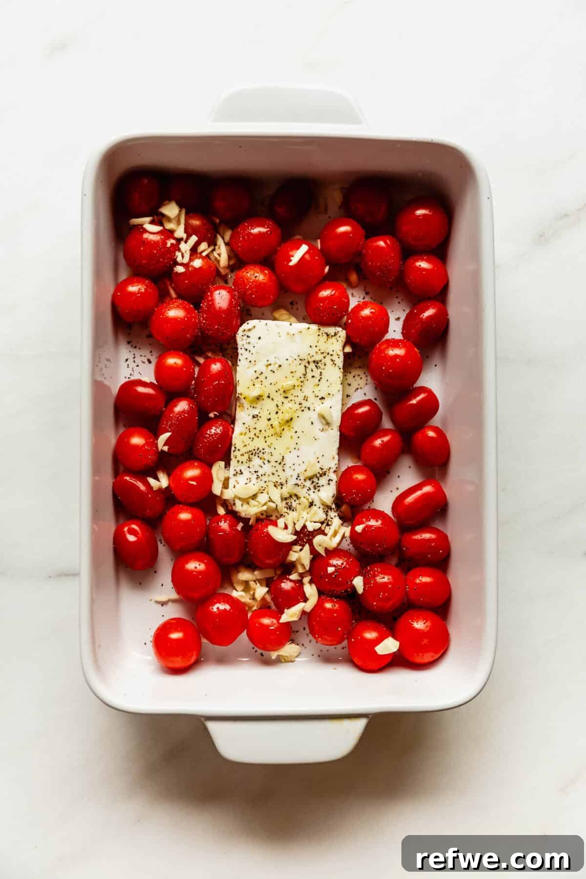 Creamy Baked Feta Orzo with Cherry Tomatoes and Spinach 4 Unbaked dish of cherry tomatoes, garlic, and feta cheese ready for the oven.