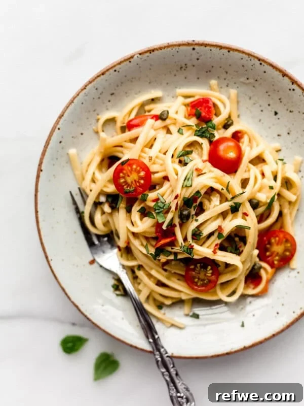 linguine pasta with cherry tomatoes on a white ceramic plate