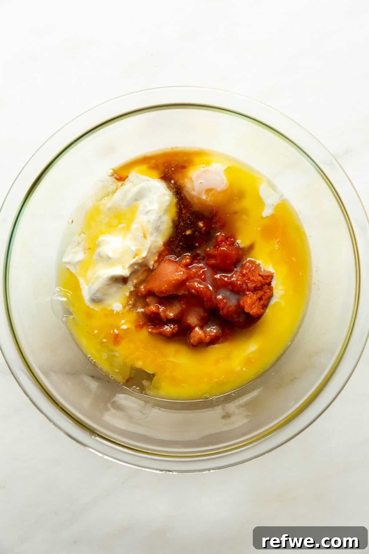 Moist Pumpkin Muffins with Cottage Cheese 4 Wet ingredients for cottage cheese pumpkin muffins, including eggs, cottage cheese, melted butter, and pumpkin puree, in a glass mixing bowl.
